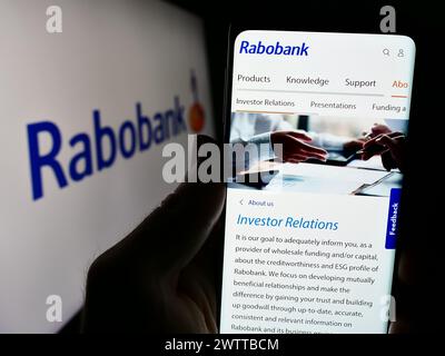 Personne tenant le téléphone portable avec la page web de la société bancaire néerlandaise Cooperatieve Rabobank U.A. devant le logo. Concentrez-vous sur le centre de l'écran du téléphone. Banque D'Images