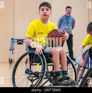 Winchburgh Academy, West Lothian, Écosse, Royaume-Uni, 19 mars 2024. Festival Parasport pour les enfants handicapés : Scottish Disability Sport organise une série de manifestations à l'échelle nationale pour offrir aux jeunes handicapés physiques, malentendants et malvoyants la possibilité d'essayer un large éventail de sports dispensés par des entraîneurs qualifiés locaux. Photo : les enfants essaient le basketball en fauteuil roulant même s'ils n'utilisent pas de fauteuil roulant. Crédit : Sally Anderson/Alamy Live News Banque D'Images