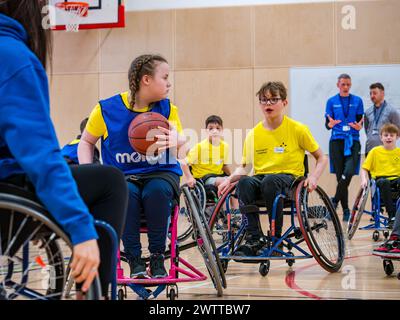 Winchburgh Academy, West Lothian, Écosse, Royaume-Uni, 19 mars 2024. Festival Parasport pour les enfants handicapés : Scottish Disability Sport organise une série de manifestations à l'échelle nationale pour offrir aux jeunes handicapés physiques, malentendants et malvoyants la possibilité d'essayer un large éventail de sports dispensés par des entraîneurs qualifiés locaux. Photo : les enfants essaient le basketball en fauteuil roulant même s'ils n'utilisent pas de fauteuil roulant. Crédit : Sally Anderson/Alamy Live News Banque D'Images