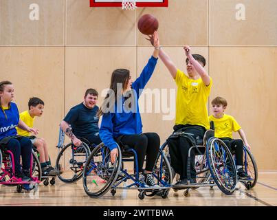 Winchburgh Academy, West Lothian, Écosse, Royaume-Uni, 19 mars 2024. Festival Parasport pour les enfants handicapés : Scottish Disability Sport organise une série de manifestations à l'échelle nationale pour offrir aux jeunes handicapés physiques, malentendants et malvoyants la possibilité d'essayer un large éventail de sports dispensés par des entraîneurs qualifiés locaux. Photo : les enfants essaient le basketball en fauteuil roulant même s'ils n'utilisent pas de fauteuil roulant. Crédit : Sally Anderson/Alamy Live News Banque D'Images