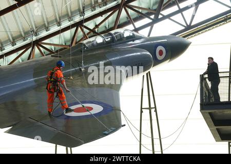 Les spécialistes industriels de l'accès par câble descendent en rappel au Royal Air Force Museum Midlands, à Cosford, près de Telford, Shropshire, pour accéder à une exposition d'avions suspendus exposée à la National Cold War Exhibition, lors du nettoyage et de la maintenance annuels des avions de haut niveau. Date de la photo : mardi 19 mars 2024. Banque D'Images