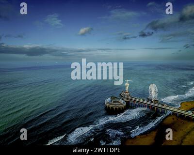 Une vue aérienne sereine d'un quai avec un parc d'attractions s'étendant dans la mer tranquille Banque D'Images