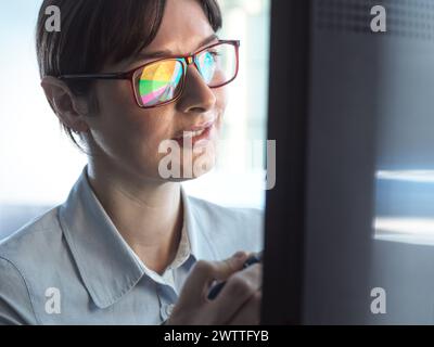 Femmes professionnelles concevant un diagramme circulaire sur un ordinateur pour illustrer les statistiques d'entreprise. Banque D'Images