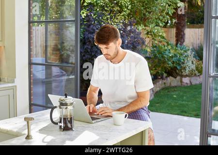 Homme travaillant sur un ordinateur portable à une table extérieure. Banque D'Images