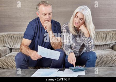 Deux adultes examinant des documents financiers sur un canapé Banque D'Images