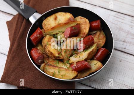 Pommes de terre frites avec de fines saucisses fumées sèches sur une table en bois blanc Banque D'Images