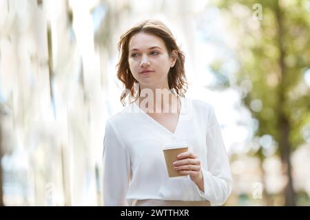 Femme tenant une tasse de café à l'extérieur Banque D'Images
