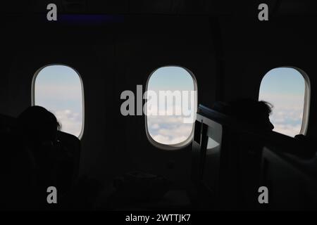 Fenêtres d'avion avec vue sur le ciel, les nuages et les ailes. Intérieur de cabine d'avion en vol Banque D'Images