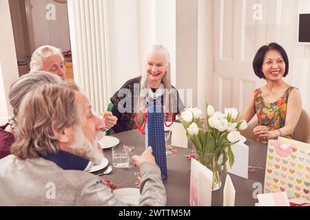Groupe d'adultes profitant d'une célébration à une table à manger. Banque D'Images