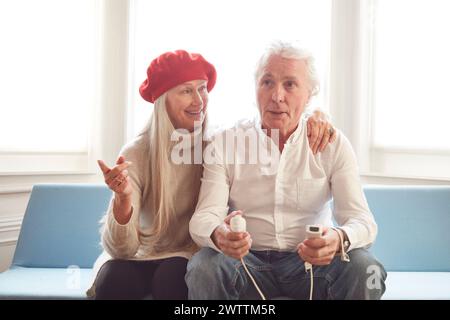 Couple âgé profitant d'un jeu vidéo ensemble sur un canapé. Banque D'Images