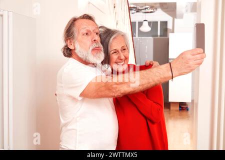 Couple senior prenant un selfie à la maison Banque D'Images