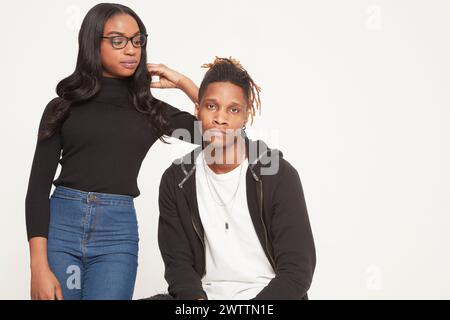 Femme debout à côté de l'homme assis sur fond blanc. Banque D'Images