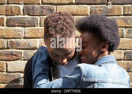 Deux personnes souriant et s'embrassant contre un mur de briques Banque D'Images