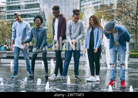 Groupe d'amis appréciant les jets de fontaine Banque D'Images