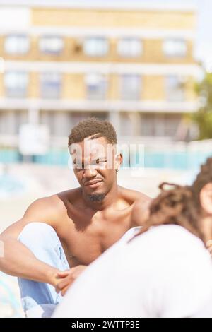 Jeune homme assis dehors dans la conversation Banque D'Images