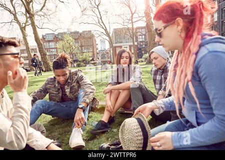Groupe d'amis assis sur l'herbe dans un parc Banque D'Images