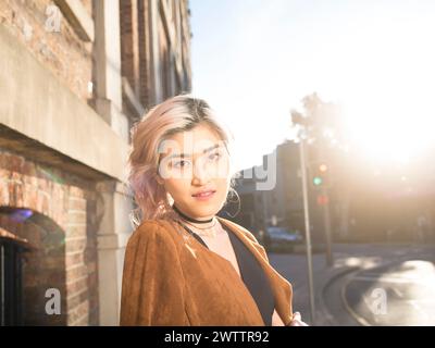 Femme avec les cheveux roses dans le coucher du soleil urbain Banque D'Images