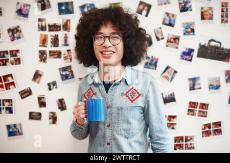 Homme aux cheveux bouclés tenant une tasse bleue Banque D'Images