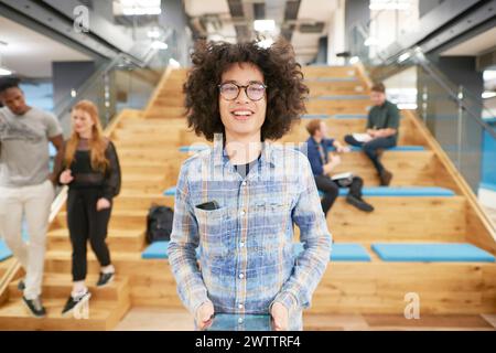 Personne souriante avec des lunettes dans les escaliers du bureau Banque D'Images