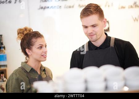 Deux baristas ont engagé une conversation derrière un comptoir de café. Banque D'Images