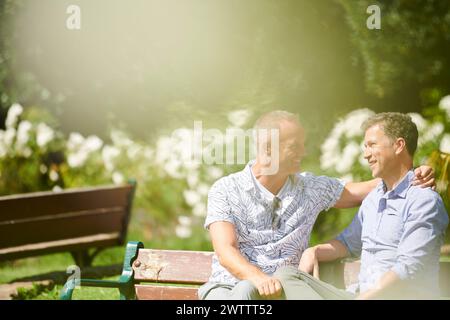 Deux hommes souriants et assis sur un banc de parc Banque D'Images
