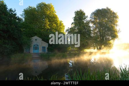 Lever du soleil sur un lac tranquille avec une petite maison Banque D'Images