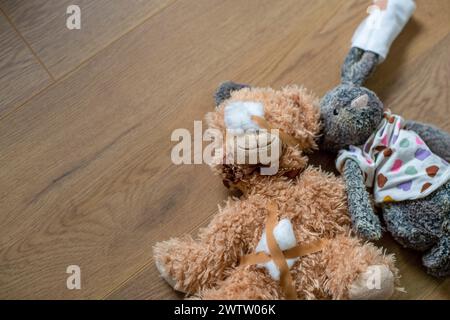 Un ours en peluche cher à un enfant et une poupée couchée sur un plancher en bois Banque D'Images