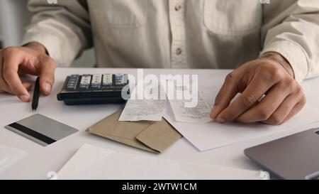 Homme méconnaissable homme d'affaires Guy homme d'affaires utilisant la calculatrice et l'ordinateur portable calculer les coûts d'argent de revenu comptant les factures de bureau vérifier les dépenses écrire Banque D'Images