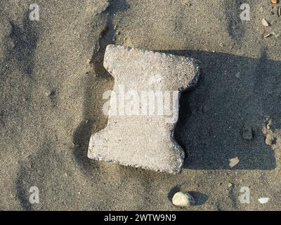 Une tuile grise sur le sable. Matériaux de construction abandonnés. Pierre dure Banque D'Images