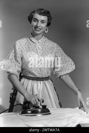 Femme d'âge moyen, bien habillée, avec boucles d'oreilles repassage Banque D'Images