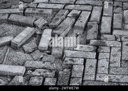 Gros plan d'un pavé de briques endommagé et inégal offrant une texture urbaine abstraite Banque D'Images