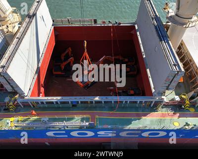 YANTAI, CHINE - 19 MARS 2024 - Une grue charge des excavatrices exportées vers le Brésil dans le cargo «Yantai - Brésil» au port de Yantai, Shandong pr Banque D'Images