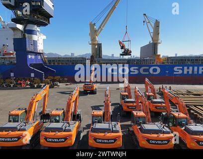 YANTAI, CHINE - 19 MARS 2024 - Une grue charge des excavatrices exportées vers le Brésil dans le cargo «Yantai - Brésil» au port de Yantai, Shandong pr Banque D'Images