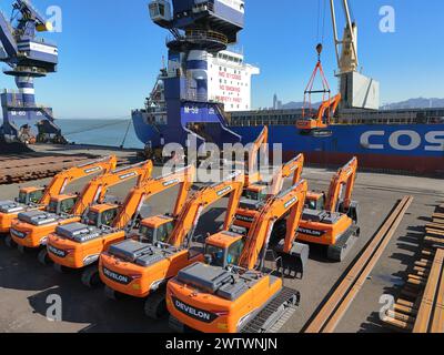 YANTAI, CHINE - 19 MARS 2024 - Une grue charge des excavatrices exportées vers le Brésil dans le cargo «Yantai - Brésil» au port de Yantai, Shandong pr Banque D'Images