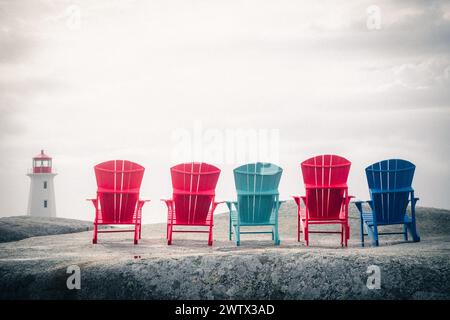 Rangée de chaises Adirondack rouges, bleues et turquoises sur les rochers devant le phare de Peggy's Cove en Nouvelle-Écosse, Canada Banque D'Images