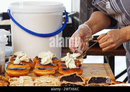 Production de desserts au marché alimentaire de rue Farmers, section centrale du chef décorant des beignets bavarois. Banque D'Images