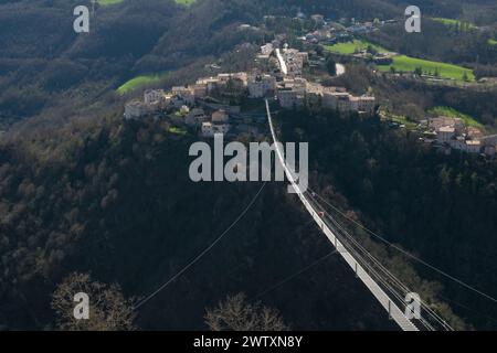 Vue panoramique hivernale du pont tibétain à Sellano, Ombrie. Passerelle haute suspension sur une vallée aux couleurs froides saisonnières et ville historique Banque D'Images