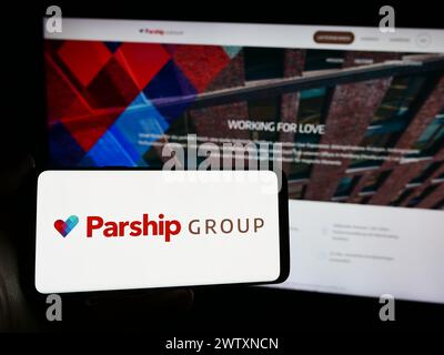 Personne tenant un smartphone avec le logo de la société allemande de rencontres en ligne ParshipMeet Holding GmbH en face du site. Concentrez-vous sur l'affichage du téléphone. Banque D'Images