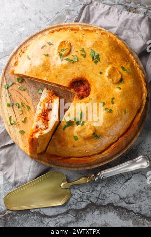 Empanada gallega est une tarte salée traditionnelle de la garniture espagnole est avec de la viande, du poivron, de la tomate et de l'oignon en gros plan sur la table. V Banque D'Images