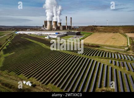 Eschweiler, Allemagne. 21 mars 2024. Un champ avec panneaux solaires se trouve devant la centrale au lignite de RWE Weisweiler. La centrale électrique de Weisweiler est une centrale électrique à charge de base exploitée par RWE Power utilisant du lignite. Le lignite provient de la mine à ciel ouvert d'Inden. Crédit : Oliver Berg/dpa/Alamy Live News Banque D'Images