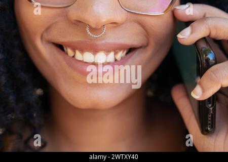 Gros plan jeune femme afro-américaine souriante parlant sur smartphone Banque D'Images