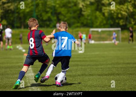 Jeunes joueurs dans Sports Duel. Deux garçons de l'école jouant un match de football de compétition.les enfants frappent le ballon pendant la Ligue de football junior Banque D'Images