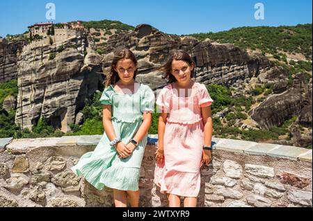 Portrait d'enfants visitant le célèbre monastère des Météores en Grèce. Filles jumelles posant dans les Météores avec un monastère célèbre en arrière-plan sur un sunn Banque D'Images