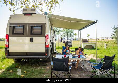 Camping familial avec camping-car dans les campings en Grèce ou en Croatie. Famille détente avec camping-car, chaises et table en vacances. Banque D'Images