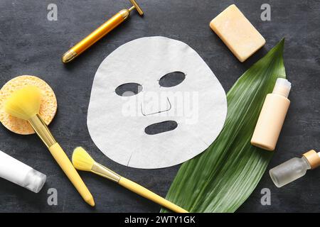 Masque facial en feuille avec différents produits cosmétiques et feuille sur fond noir Banque D'Images