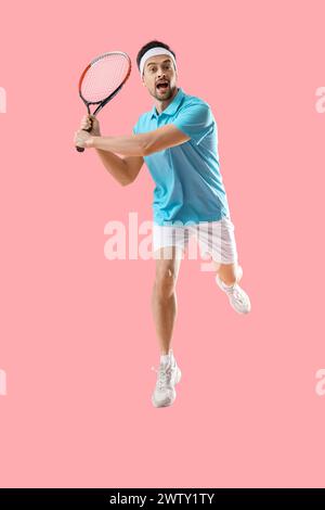 Portrait de joueur de tennis masculin sautant sur fond rose Banque D'Images