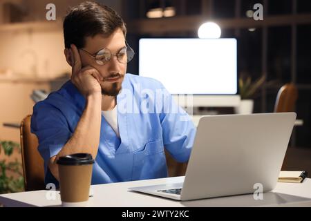 Infirmier fatigué travaillant le soir à table en clinique Banque D'Images