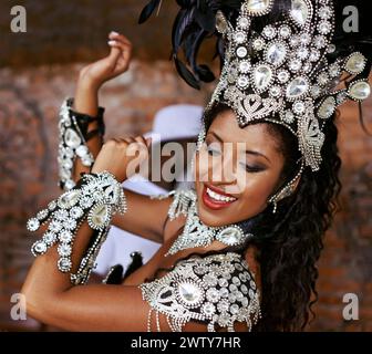 Interprète, samba et danse avec spectacle, sourire et maquillage pour concert ou fête. Femme brésilienne, célébration et plume pour la culture, le talent et la créativité Banque D'Images