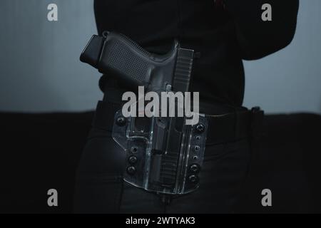 La fille a un pistolet dans un étui transparent sur une ceinture sur sa ceinture, photo en gros plan. Banque D'Images