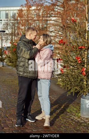 Portrait de jeunes gens attrayants, couple charmant bénéficiant de l'atmosphère chaleureuse sur la foire dans la veille de Noël. Passer du temps ensemble. Concept de national Banque D'Images